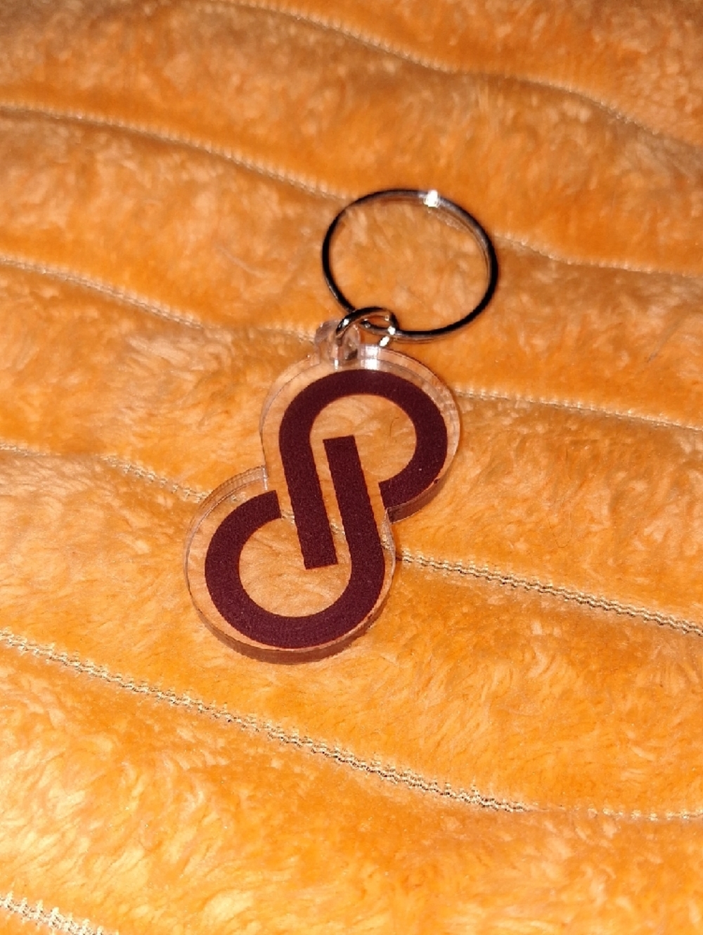 Clear acrylic keychain featuring a bold purple interlocking Poshmark logo.